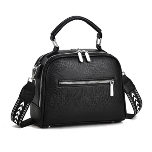 Detail of black crossbody bag featuring pebbled leather texture and woven shoulder strap