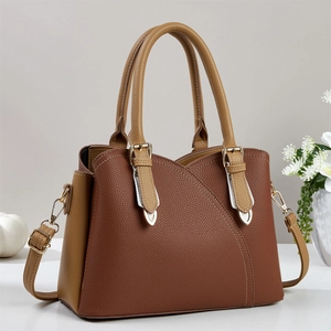 Detail of a two-tone brown tote bag with pebble leather texture and adjustable strap