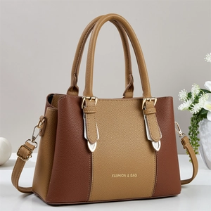 Detail of high-quality brown lychee leather texture and gold logo on tote handbag