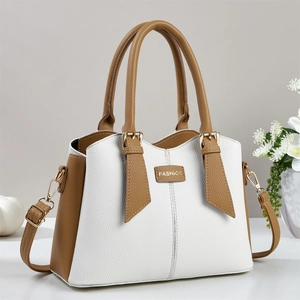 Detail of lychee textured leather and gold-tone FASHION metal plaque on the handbag