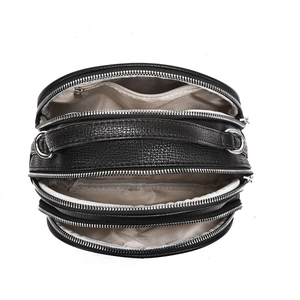 Close-up of black pebble leather crossbody bag with three zipper layers and internal lining