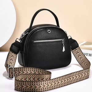Detail of black pebbled leather crossbody bag with geometric ethnic weave strap and silver zips
