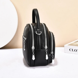 Close-up of black lychee grain leather multi-layer shoulder bag with silver zippers