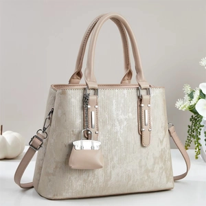 Elegant beige textured handbag with curved handle and matching mini charm accessory