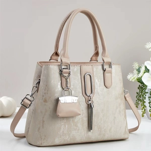 Beige faux leather tote bag with metallic texture, tassel charm and top handles