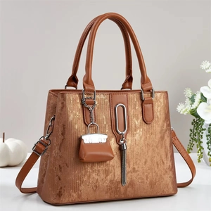 Brown textured leather handbag with fringe pendant and adjustable shoulder strap