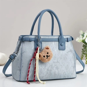 Sac à main bleu clair texturé avec pendentif ours dans un décor de maison élégant