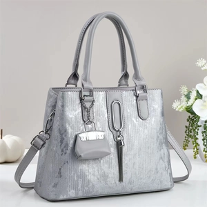 Chic silver metallic tote bag with tassels and shoulder strap on a minimalist desk