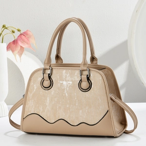 Detail of beige tote bag featuring striped fabric panel and fashion text on surface