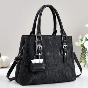 Sac à main noir texturé avec boucles argentées et breloque sur fond blanc élégant