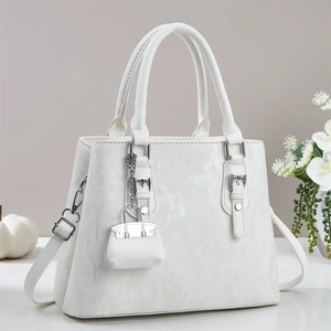 Détail d'un sac à main élégant en cuir PU blanc avec finitions argentées et pendentif
