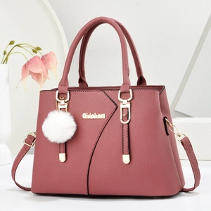 Pink lychee texture handbag with gold logo and fluffy white pompom charm on white background