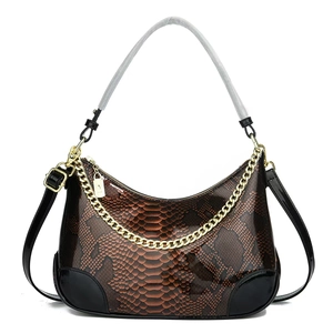 Detailed view of snake skin texture and gold chain on brown faux leather handbag