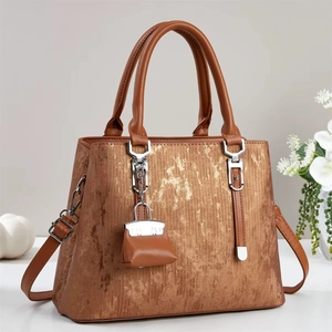 Detail of metallic bronze handbag texture with silver hardware and mini charm