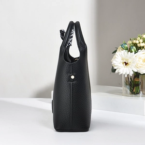 Detail view of black lychee grain leather bucket bag with decorative silk scarf and gold stud