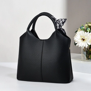 Close-up of black lychee grain bucket bag with a geometric polka dot silk scarf handle