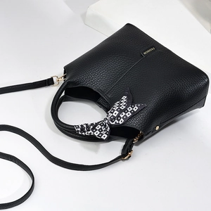 Detail of black lychee grain leather bucket bag with silk scarf handle and gold buckle
