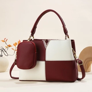 Détail d'un sac seau bicolore bordeaux et crème avec logo V en métal et mini porte-monnaie