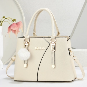 Detail of off-white lychee leather bag with gold hardware and plush ball charm