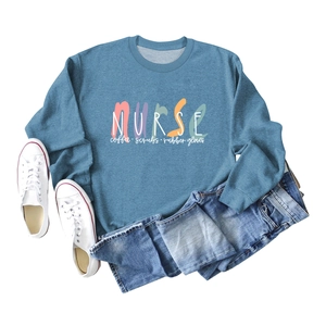 Flat lay of blue nurse-themed sweatshirt with coffee scrubs print and denim pants