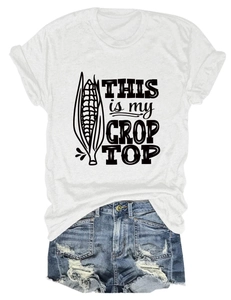 Detailed flat lay of white crop top featuring corn graphic and pun print with denim shorts