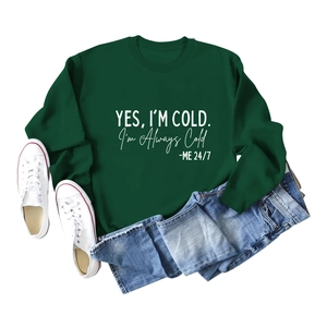 Détail d'un sweat vert foncé avec impression artistique blanche YES I'M COLD sur le devant