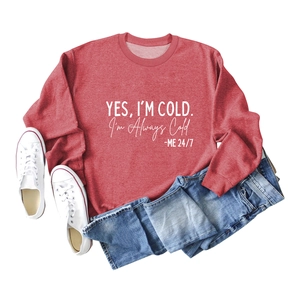 Mise à plat d'un sweat brique imprimé 'Yes I'm Cold' avec jean et baskets blanches