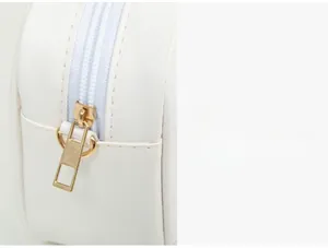 Détail de la fermeture éclair en métal doré et couture sur le sac bandoulière en cuir blanc