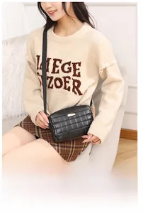 Détail du sac caméra noir matelassé avec plaque dorée et bandoulière ajustable