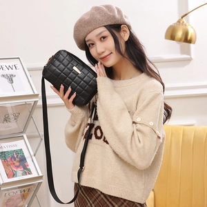 Sac bandoulière matelassé noir avec détail doré, mis en scène dans un intérieur moderne