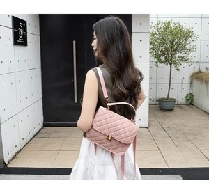 Detailed view of pink quilted handbag with gold twist lock on female model