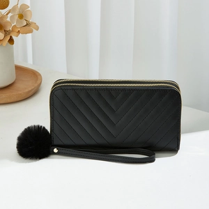 Black long double-zipper wallet with V-shaped quilting and a fluffy pompom keychain