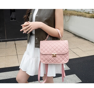 Detail of light pink quilted handbag featuring a golden clasp and detachable shoulder strap