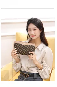Borsa a tracolla con catena stampata indossata con un outfit casual neutro sul divano
