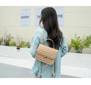 Close-up of beige quilted backpack with elegant gold twist lock on outdoor street background