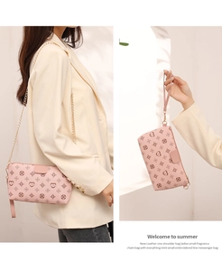 Detail of pink crossbody bag with heart pattern, gold chain strap and leather handle