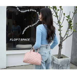 Détail d'un sac à main rose matelassé avec surpiqûres losanges et logo fleur dorée
