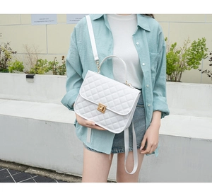 Detail showing the white quilted crossbody bag with gold metallic twist lock on a model