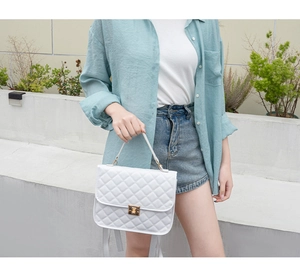Detail of white quilted backpack with gold twist lock on a modern faux leather surface