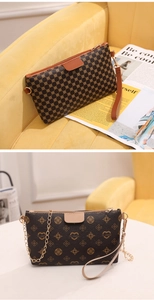 Detailed view of brown monogram crossbody bag with gold chain and heart pattern