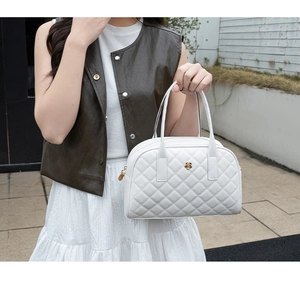 Sac à main blanc matelassé avec logo fleur dorée porté dans un style urbain chic