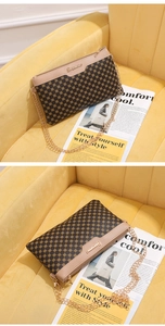Dettaglio borsa a tracolla marrone stampata con catena dorata su sfondo di velluto giallo