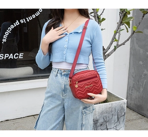 Detail of red V-quilted crossbody bag with gold hardware and adjustable strap