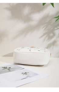 Close-up of elegant floral embroidery and butterfly detail on the white crossbody bag