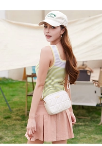 Detail of a beige quilted crossbody bag featuring a golden logo plate and zipper closure