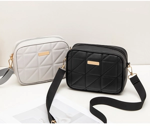 Close-up of quilted crossbody bags in black and grey with wide textile straps