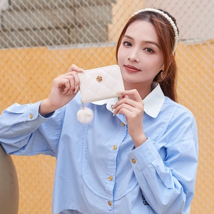 Portafoglio trapuntato beige con logo a rosa dorata e pompon, mostrato dalla modella