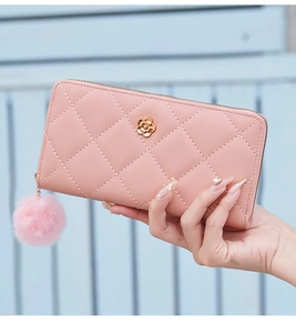 Pink quilted wallet with gold flower accent and plush pompom charm detail