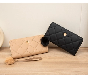 Detail of quilted long wallets with gold flower hardware and plush pompom charms