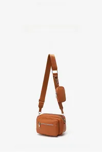 Detail of brown faux leather crossbody bag showing dual-bag design and wide nylon strap